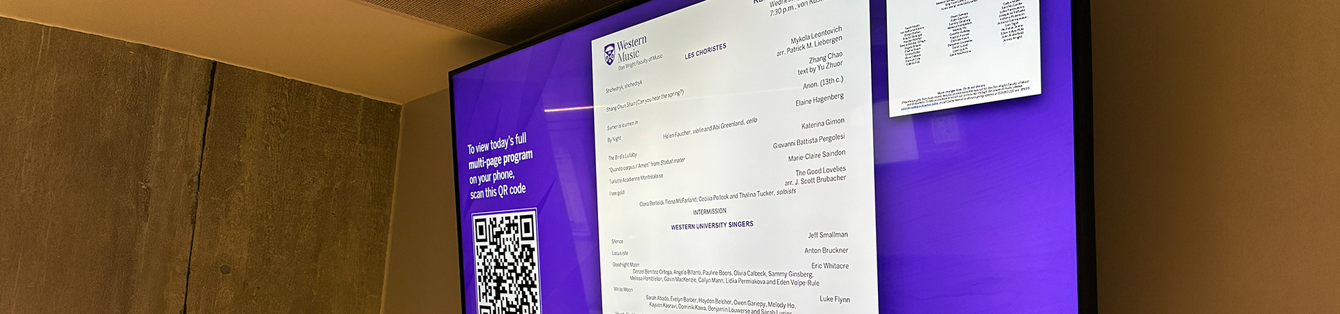 A digital screen outside von Kuster Hall displaying a concert program