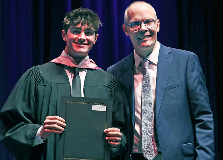 Student award winner on stage with a faculty member