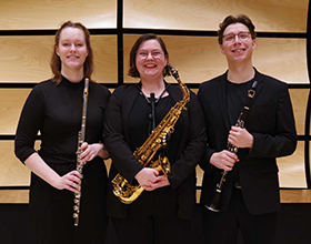 Three chamber music students smiling for the camera while holding their instruments