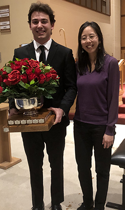 Kai Melconian holding a trophy filled with roses with his piano teacher Angela Park