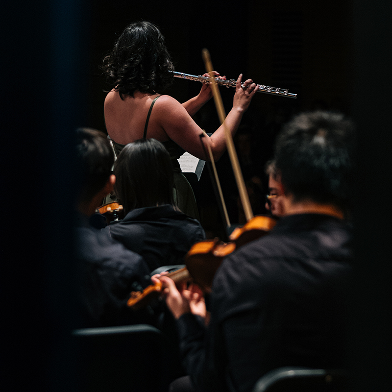 A flute player performing a concerto with an orchestra
